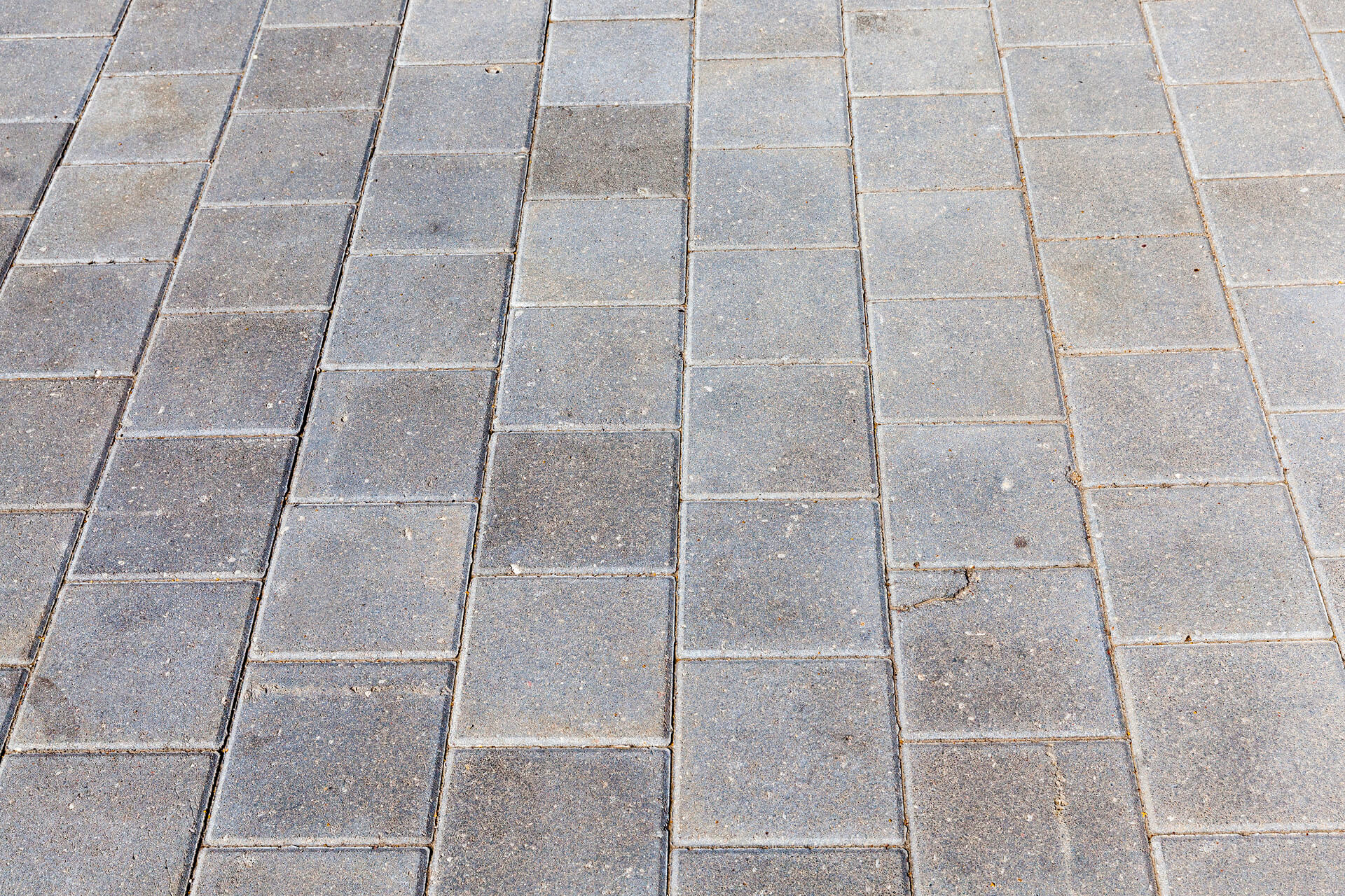 medium-vecteezy_concrete-tiles-on-the-road_9720347_medium (1) Gray rectangular stone pavers arranged in a linear pattern on a walkway or patio surface.