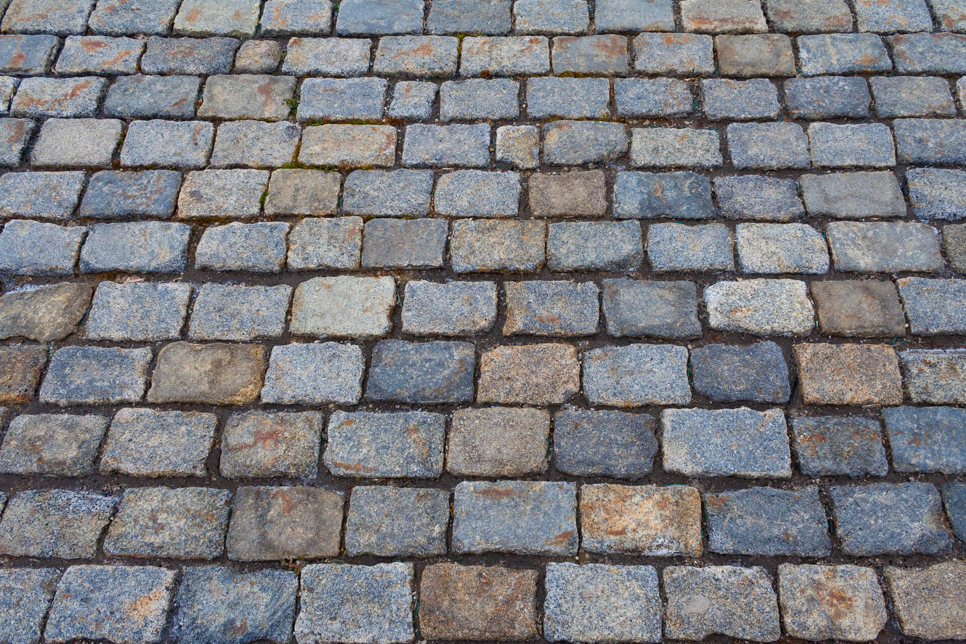medium-vecteezy_perspective-view-on-a-old-stone-pavement_47559630_medium (1) (1) Weathered cobblestone street with gray and tan colored stones arranged in irregular rows.Retry